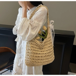 Détail du sac cabas en paille tissée main avec nœud en dentelle blanche et texture