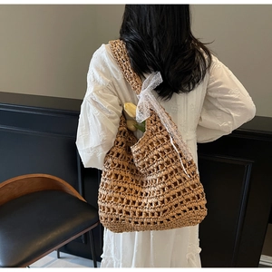 Macro shot of large straw tote bag featuring hollow mesh weave and white lace bow detail