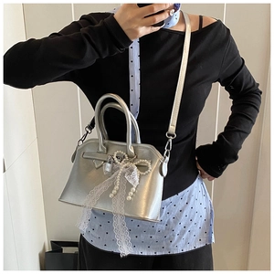 Detail shot of a silver handbag with lace trim, bead bow and metal padlock detail