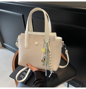 Détail du sac cabas beige tissé avec breloque ourson et lanières en cuir marron