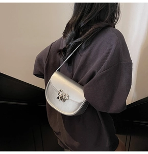 Detailed view of silver crescent saddle bag with metallic bow buckle worn by model