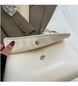 Close-up of silver magnetic clasp and chain strap on off-white leather tote bag