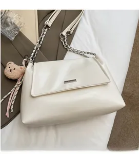 Detail view of soft cream tote bag with metal chain strap and cute bear plush charm