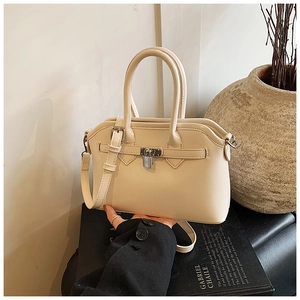 Close-up of cream PU leather handbag featuring metallic lock and adjustable strap