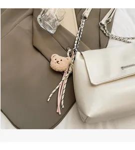 Macro shot of cream leather bag texture with silver plaque and bear charm detail