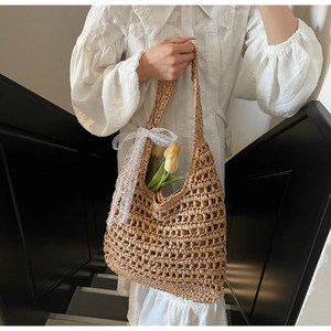 Detail view of woven straw tote bag featuring delicate white lace bow and vintage texture