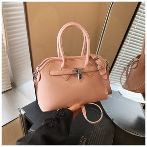 Detail view of pink leather handbag with metal lock hardware and detachable strap