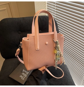 Sac seau rose tissé avec charm ours mignon et détails de glands sur une chaise