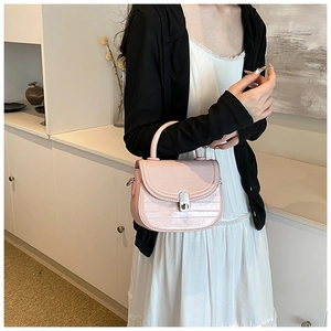 Detail view of pink patent leather saddle bag with crocodile texture and silver twist lock