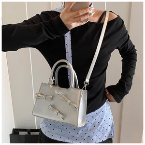 Detail view of silver bow-knot bag featuring metallic texture and adjustable shoulder strap