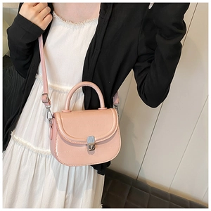 Detail of pink saddle bag with silver clasp shown crossbody on a model's outfit