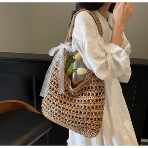 Détail du sac cabas en paille tissée avec nœud en dentelle et accents de tulipes