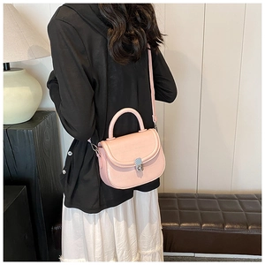 Pale pink saddle bag with crocodile texture shown on model in a modern interior setting