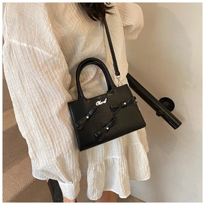 Fashionable black crossbody bag featuring pearl bows and metallic logo detail
