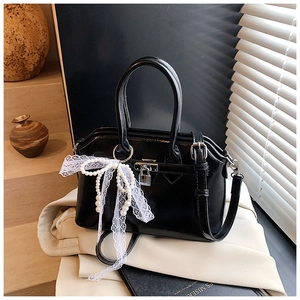 Detail of black PU leather handbag with metallic lock, lace bow, and pearl charm