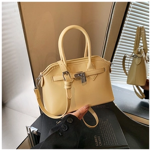 Detail of yellow faux leather trapezoid handbag with dual handles and metal padlock