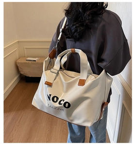 Rear view of model carrying a beige large travel tote bag with brown straps and NOCO logo