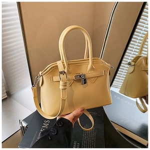 Close-up of creamy yellow satchel bag with metallic twist-lock and leather texture