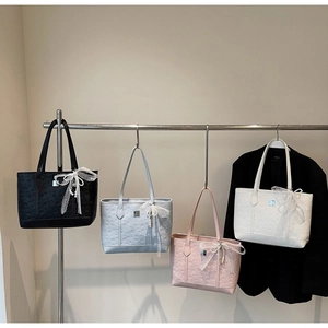 Detail of four colorful tote bags with embossed texture and lace pearl bow charms