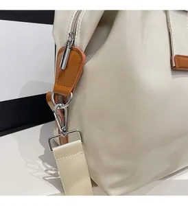 Detailed close-up of glossy cream travel bag featuring bright silver metal hardware and straps