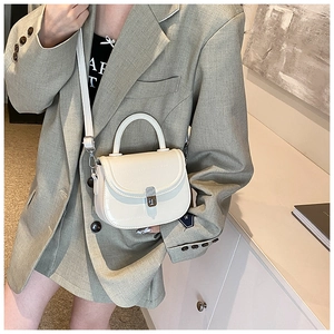 Close-up of white crocodile pattern saddle bag with silver metallic rotary lock detail