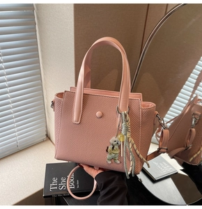 Détail d'un sac seau rose tressé avec pendentif chiot et poignée en cuir élégante