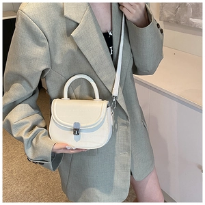 Detail of cream saddle bag with embossed leather texture and silver rotating lock