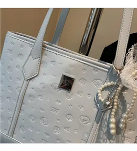Detail of light blue embossed leather tote bag with silver plate and pearl lace charm