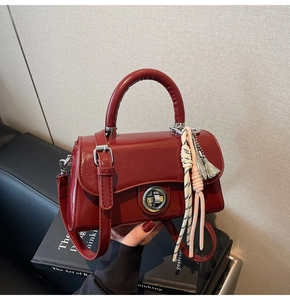 Détail du petit sac carré en cuir verni rouge avec boucle en métal et gland tissé décoratif