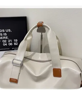 Detail of cream travel bag showing durable brown leather handles and premium metal buckles