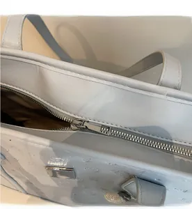 Detail of silver smooth zipper closure on ostrich textured light blue tote bag