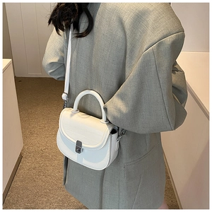 Minimalist white saddle bag shown as a crossbody on a model wearing a chic blazer