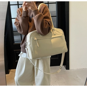 Détail d'un grand sac de voyage beige en cuir avec bandoulière réglable et poche avant