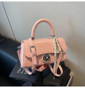 Détail du sac à main rose avec fermoir rotatif en métal et pendentif en corde tressée