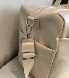 Dettaglio dei ganci metallici a D e della tracolla beige sulla borsa tote di classe