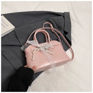 Close-up of pink crossbody bag with elegant lace bow and pearl butterfly charm