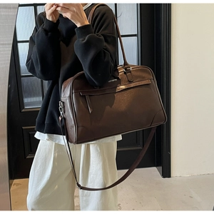 Vue détaillée du sac de voyage en similicuir marron foncé avec bandoulière réglable