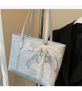Close-up of light blue embossed tote bag with elegant lace and pearl bow decoration