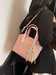 Sac seau tissé rose avec breloque ours porté par un mannequin en blazer