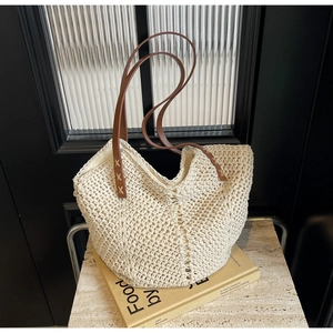 Close-up of beige crochet tote bag showing intricate knit texture and brown leather strap