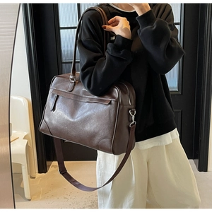Détails du grand sac de voyage en cuir marron foncé avec bandoulière et poignées chic