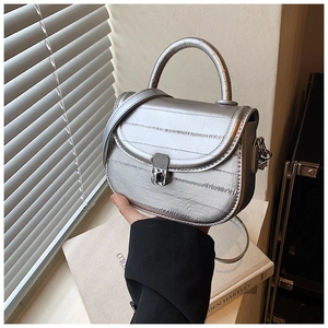 Macro shot of silver metallic saddle bag featuring horizontal quilting and metal twist lock