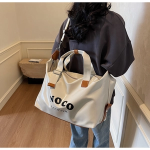 Detail of NOCO freedom white patent leather tote bag with brown leather handles and logo