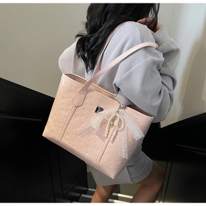 Pink embossed leather tote bag with lace bow and pearl charm shown on model's shoulder