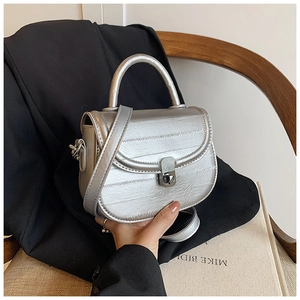 Silver saddle bag detail featuring horizontal pleated texture and metallic lock closure