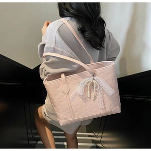 Detail of pink PU leather tote with heart embossed pattern and pearl bow charm