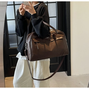 Détail d'un sac de voyage marron foncé avec lettrage blanc et garnitures argentées