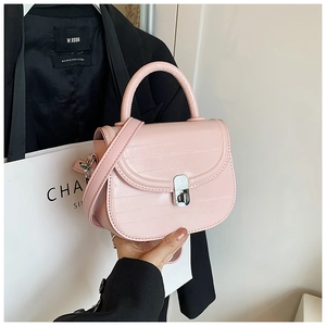 Detail of pale pink crocodile embossed saddle bag with silver metal lock and handle