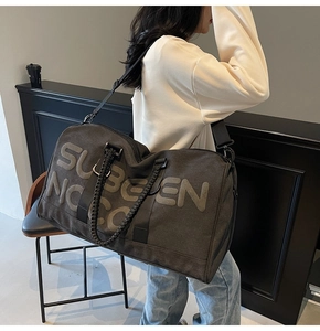 Close-up of charcoal grey travel bag with SUBGEN NOC print and textured handles
