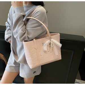 Detail of pink tote bag featuring heart embossing and pearl lace bow charm on strap